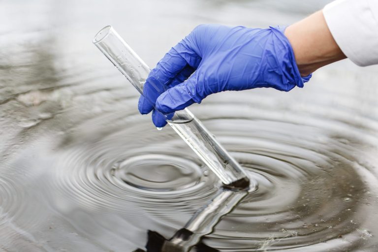 Researcher holds a test tube with water in a hand in blue glove The global push to restrict PFAS usage signals an urgent need to address the risks posed by these persistent substances.
