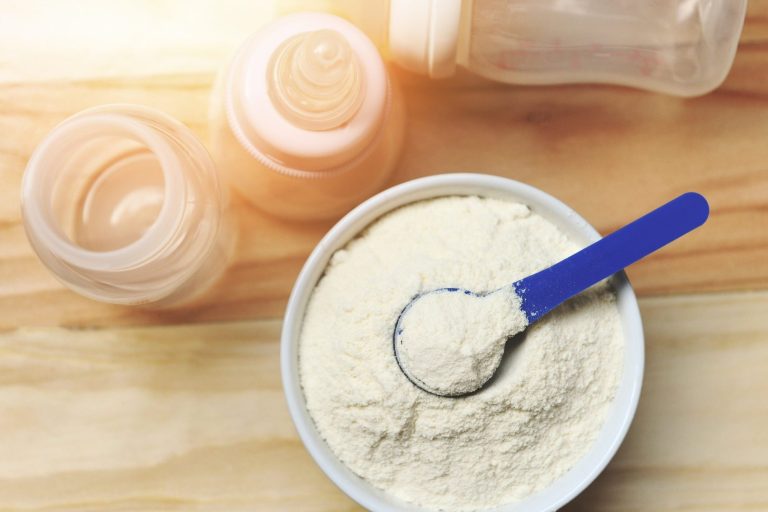 Milk powder in spoon with can and baby bottle milk bowl on woode EFSA Re-evaluation of Silicon Dioxide (E 551) as a Food Additive for Infants