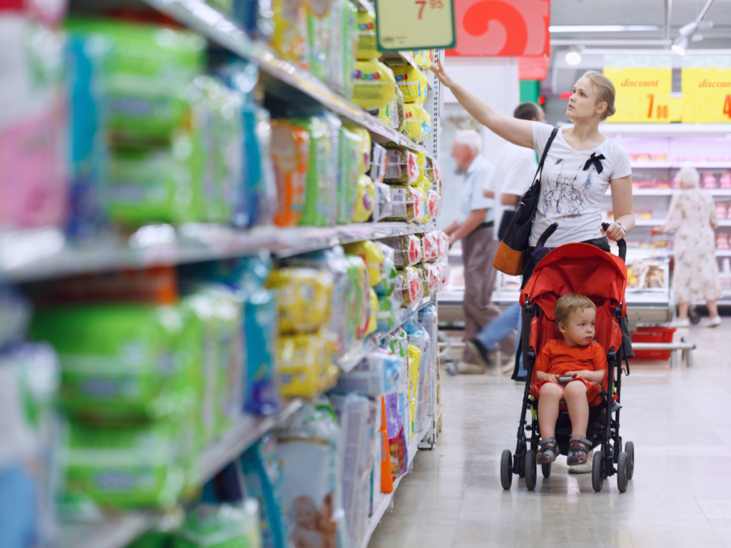 A mother and child shopping in a supermarket aisle, illustrating the practical effects and benefits of the new PPWR on product packaging for consumers.