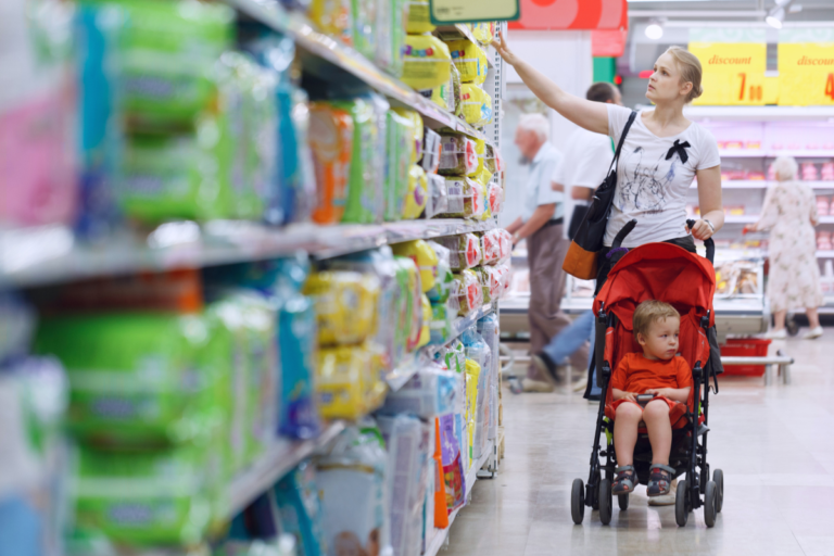 A mother and child shopping in a supermarket aisle, illustrating the practical effects and benefits of the new PPWR on product packaging for consumers.