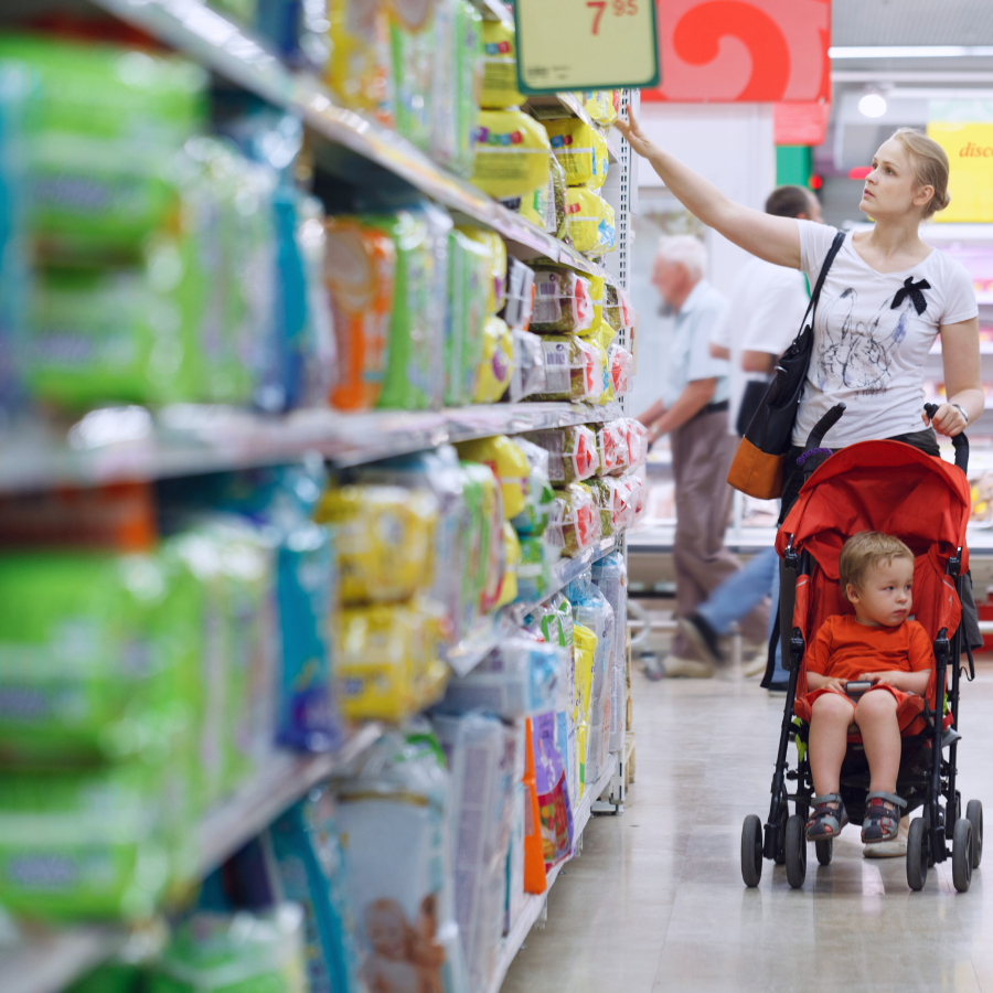 A mother and child shopping in a supermarket aisle, illustrating the practical effects and benefits of the new PPWR on product packaging for consumers.