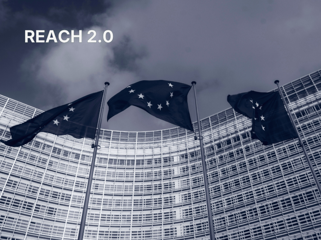 EU flags in front of the Berlaymont building in Brussels with "REACH 2.0" text overlay, illustrating the EU Commission's decision to shelve the REACH 2.0 revision.