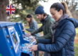 People returning plastic bottles at a reverse vending machine, illustrating how the UK DRS will work when it launches in October 2027.