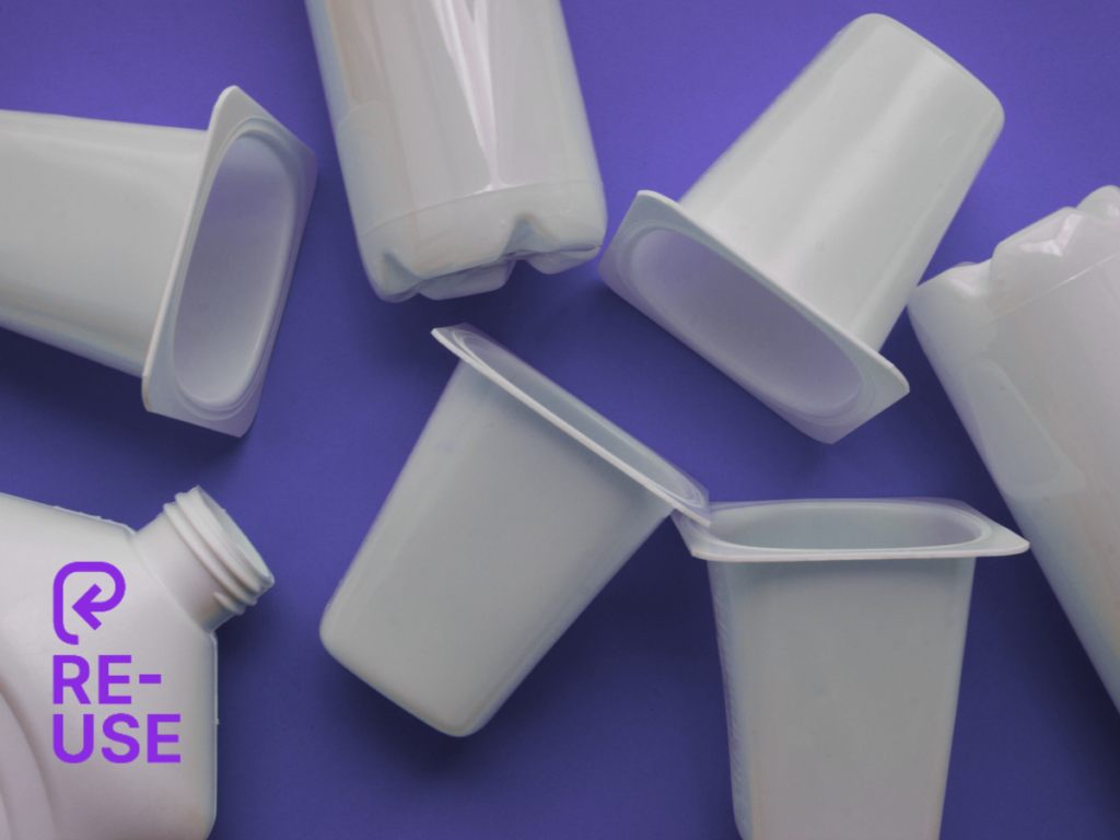 Reusable plastic containers and bottles scattered on a purple background with the PR3 reuse symbol overlay, illustrating the new global reuse packaging symbol launched by PR3: The Global Alliance to Advance Reuse.
