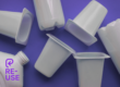 Reusable plastic containers and bottles scattered on a purple background with the PR3 reuse symbol overlay, illustrating the new global reuse packaging symbol launched by PR3: The Global Alliance to Advance Reuse.