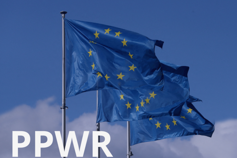 EU flags against a blue sky with "PPWR" text overlay, illustrating the industry coalition urging the EU Commission not to reopen the PPWR revision ahead of its August 2026 application date.