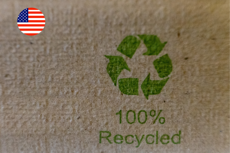 Close-up of a "100% Recycled" label printed on cardboard packaging with a US flag icon, illustrating California's packaging bills targeting recycled content and compostable labelling claims.