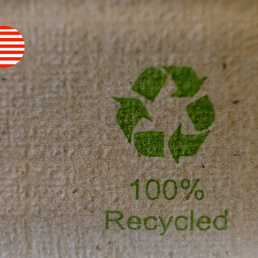 Close-up of a "100% Recycled" label printed on cardboard packaging with a US flag icon, illustrating California's packaging bills targeting recycled content and compostable labelling claims.