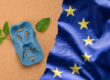 Συσκευασία από φυτικές ίνες με κλαδί φυτού δίπλα στη σημαία της ΕΕ, που απεικονίζει τη μελέτη του nova-Institute για τον ρόλο των βιοβασισμένων πλαστικών στο πλαίσιο του PPWR.