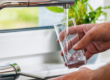 Glass being filled with drinking water from a kitchen tap, illustrating the new EU rules for products in contact with drinking water from 31 December 2026.